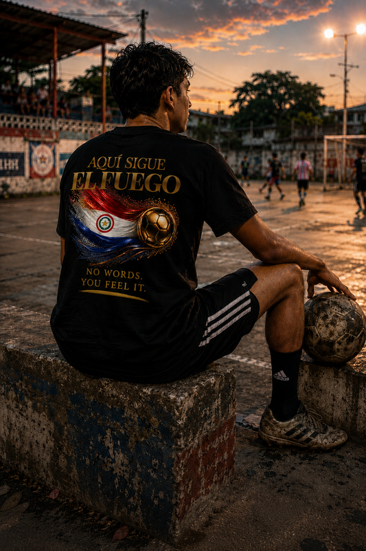 Back Print | Aquí Sigue El Fuego Tee | Gold Soccer & Paraguay Flag Design | Bilingual Edition